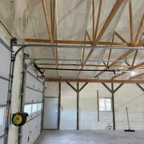 Interior warehouse with spray foam insulation applied to ceiling and walls between exposed wooden and metal beams