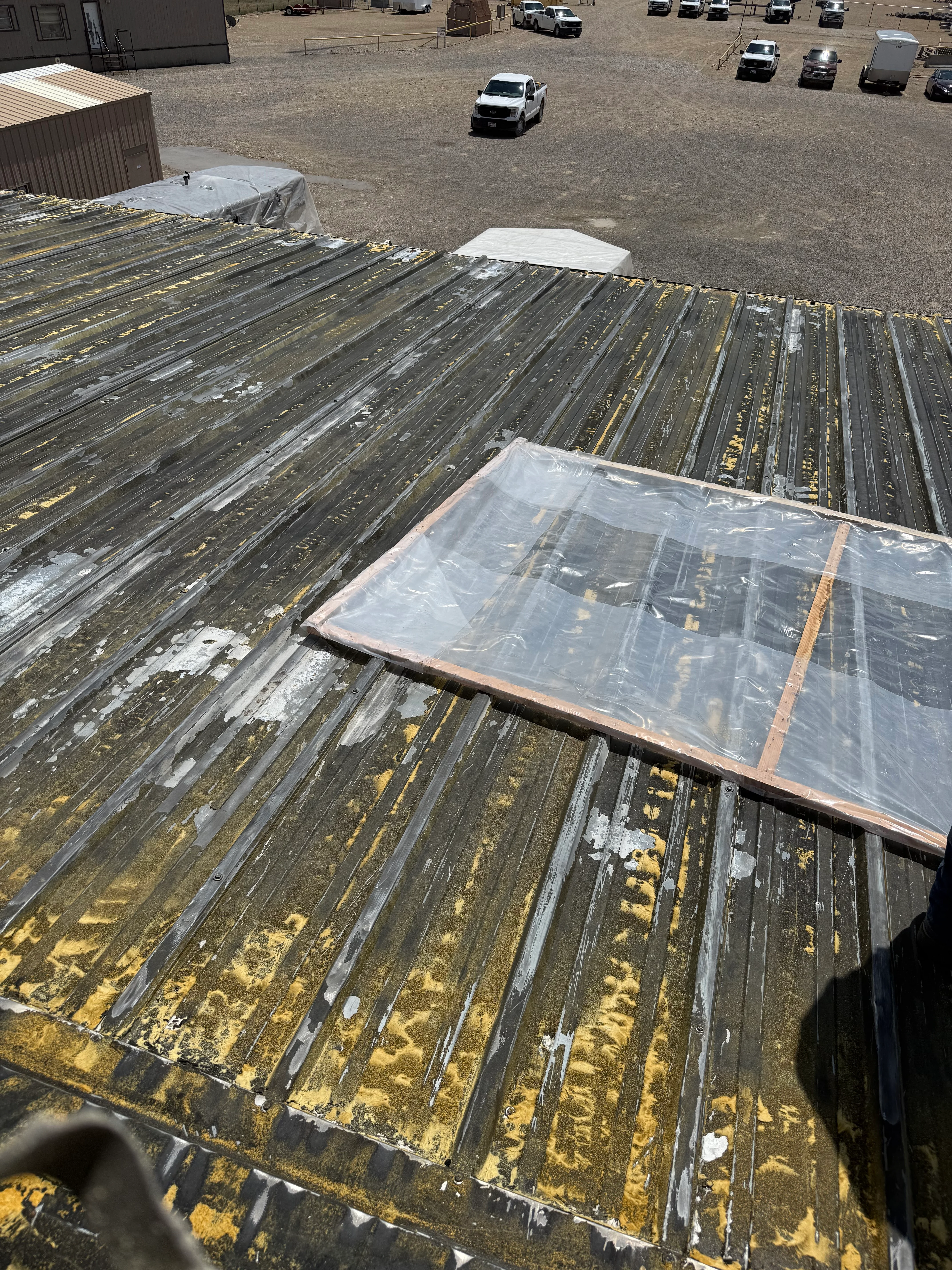 Aerial view of commercial roof with foam insulation boards and plastic protective covering installed on metal decking