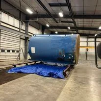 Blue spray foam insulation rig in warehouse with protective tarping