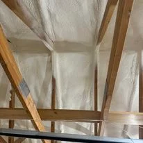 Attic insulation batts installed between wooden roof trusses and framing