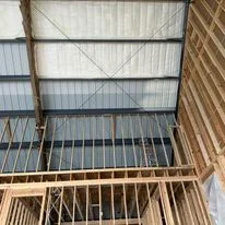 Metal roof with foam insulation board installed between wooden joists and corrugated metal roofing