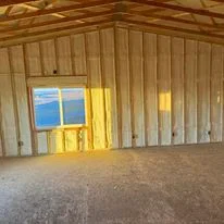 Interior view of garage with newly installed wall insulation and yellow entry door