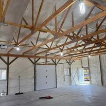 Interior of commercial warehouse with spray foam insulation installed on vaulted ceiling and walls