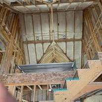Attic insulation installation with fiberglass batts between wooden roof framing