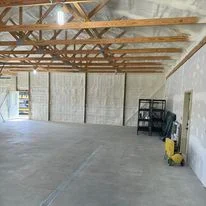 Interior of commercial warehouse with white foam insulation panels installed on walls and exposed wooden roof trusses