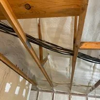 Spray foam insulation applied to wooden roof framing and beams with electrical conduit