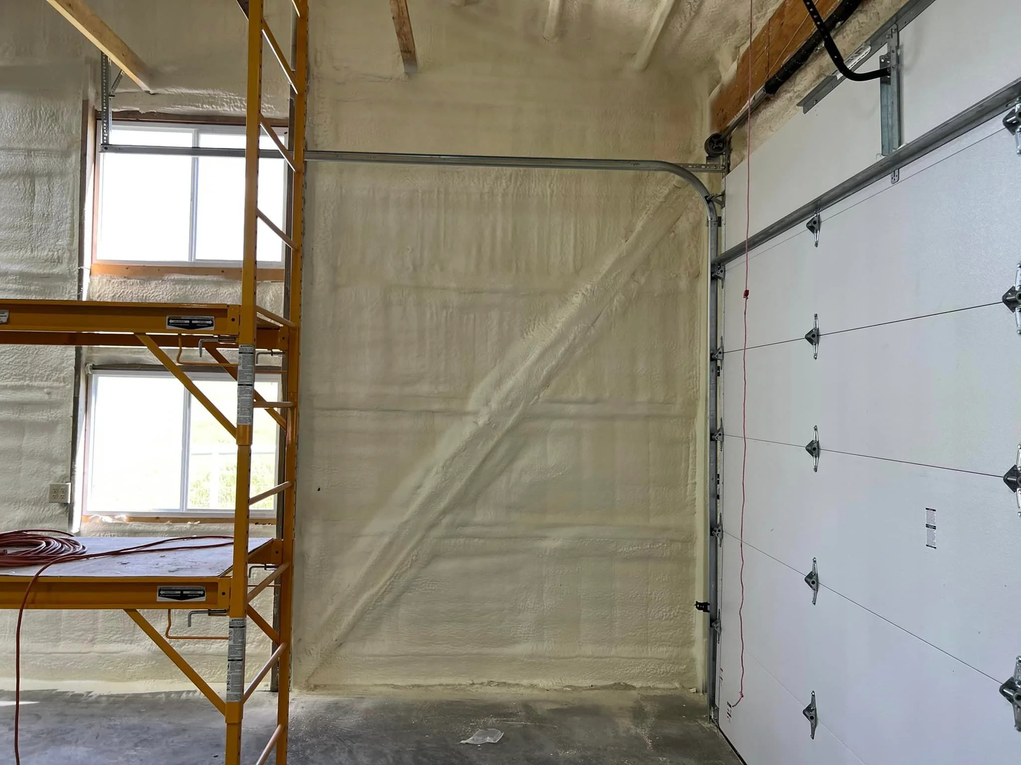 Garage interior with spray foam insulation applied to walls and ceiling during installation