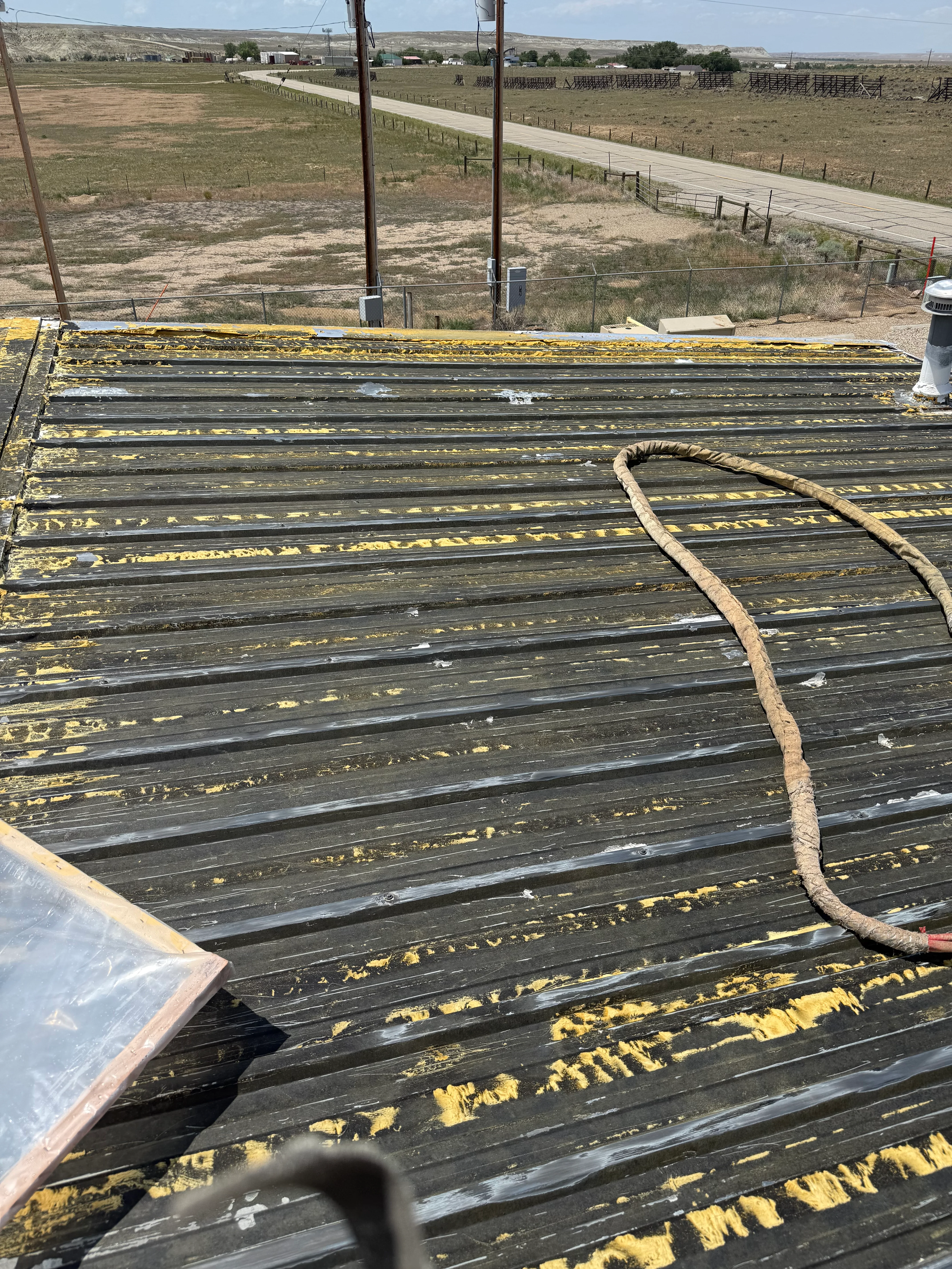 Spray foam insulation applied to agricultural building roof with yellow and black striping pattern